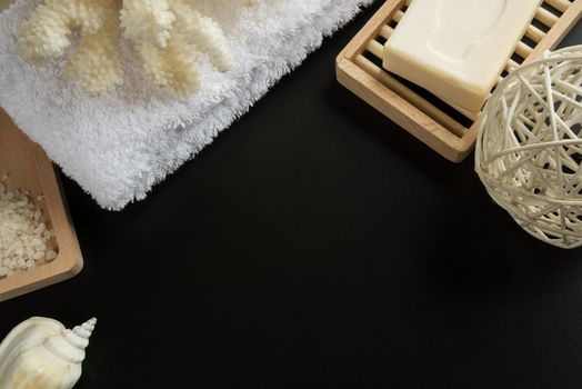 Cleansing spa accessories with sea salt, soap, white towel, and coral, isolated on a black background