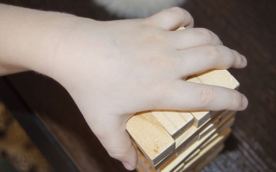 Detail of wooden block and sticks in baby's hands, the concept of teaching and education of young children