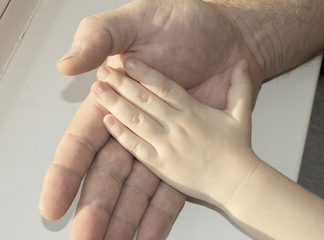 The father carefully holding in his hand the hand of a child. Happy family, care and love, father's day.