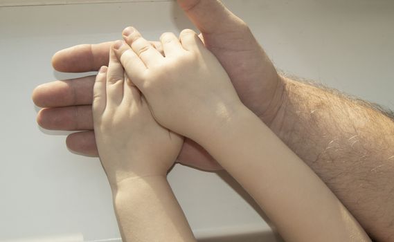 The father carefully holding in his hand the hand of a child. Happy family, care and love, father's day.