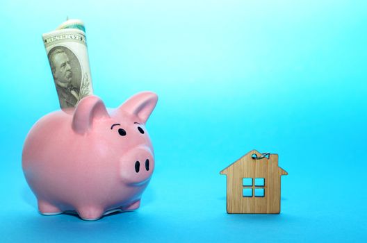 Pink piggy bank with a house on the table. Tinted. Concept of saving finances and real estate deposits