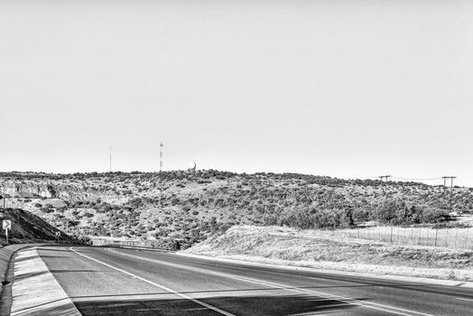 A view of the N8-road to the west of Bloemfontein in the Free State Province of South Africa. A weather radar system and cellphone tower is visible. Monochrome