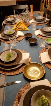 On the festive table in the wedding banquet area there are plates, glasses, candles, cutlery, the table is decorated with compositions in brown