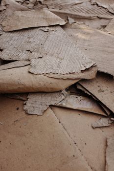 Torn brown corrugated cardboard discarded outdoors and covered in dirt