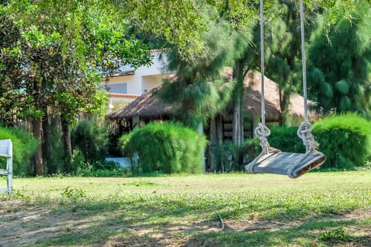 Image of wooden swing under the tree in the garden