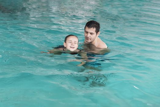 Father teaches girl to swim in the pool. Happy father teaching his little daughter to swim. Active happy child learning to swim. Little girl in a pool .