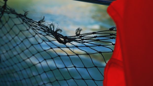 Life jacket and net on boat. Safety net on boat. Ropes on boat. Safety ropes and blue sea. Waves on the sea and safety mesh.