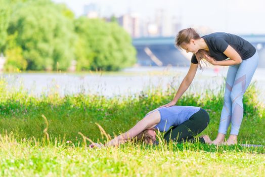 Yoga exercises under the supervision of an experienced trainer, outdoor fitness in the park