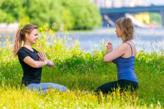 mature 40 year old woman practices yoga with an experienced trainer in a summer park