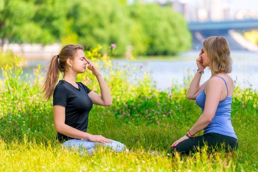 yoga in the park - meditation and breathing exercises with an experienced trainer, portrait of two women