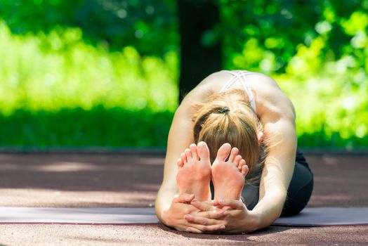 flexible yoga trainer during stretching, summer outdoor exercise