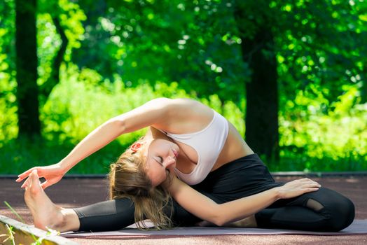 slender and flexible yoga trainer during stretching, summer outdoor exercise