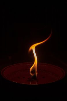 Candle flame close up on dark background, interesting flame figure, candle fire shaped like human statue