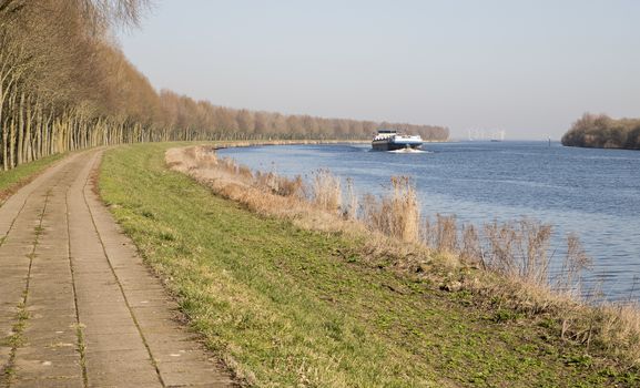 cargo ship transport in holland over the schelde rijn canal in the area of zeeland with windmills as background