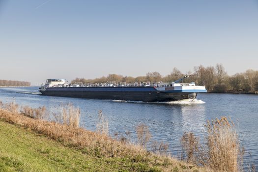 cargo ship transport in holland over the schelde rijn canal in the area of zeeland with windmills as background