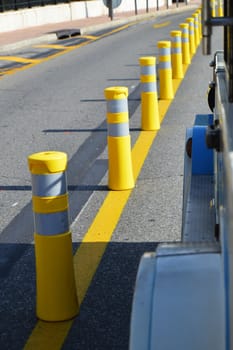 Yellow striped poles along the road divide the direction of traffic, the concept of road safety.