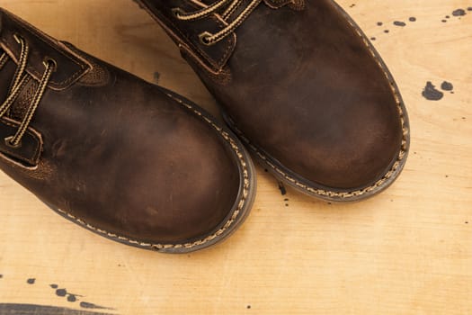 Brown men's boots, on a wooden background. Closeup isolated