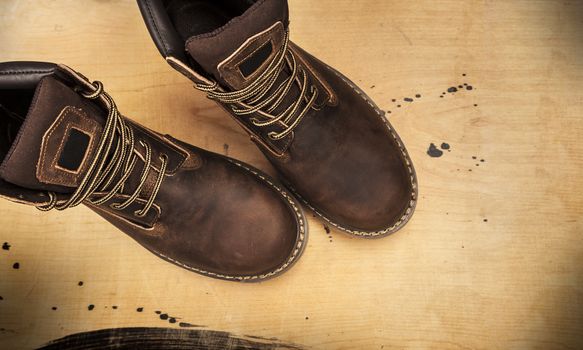 Brown men's boots, on a wooden background. Closeup isolated