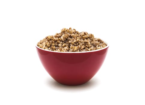 Dry buckwheat in red ceramic bowl isolated on white background. Isolated on white background.