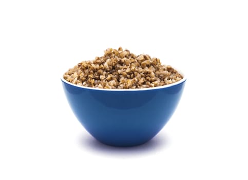 Dry buckwheat in blue ceramic bowl isolated on white background. Isolated on white background.