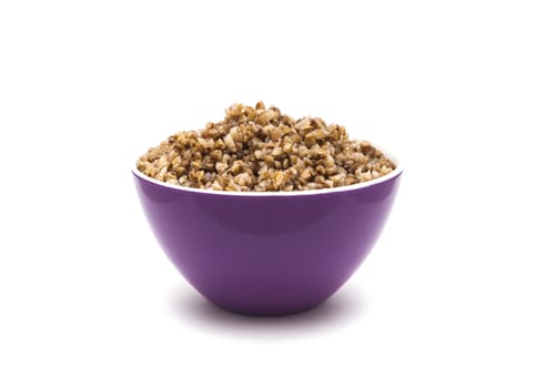 Dry buckwheat in purple ceramic bowl isolated on white background. Isolated on white background.