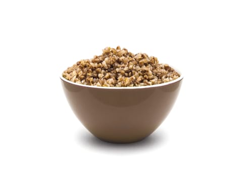 Dry buckwheat in brown ceramic bowl isolated on white background. Isolated on white background.