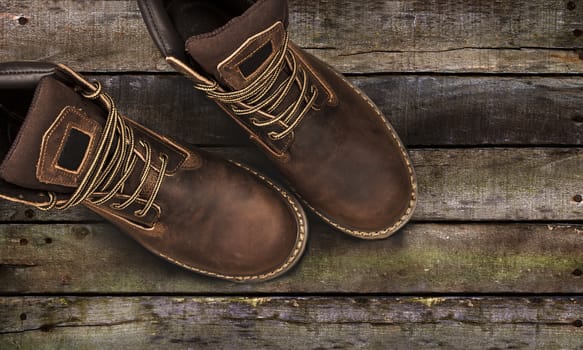 Brown men's boots, on a wooden background. Closeup isolated