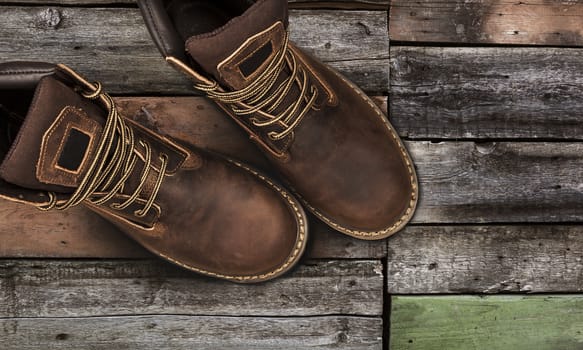 Brown men's boots, on a wooden background. Closeup isolated