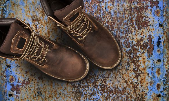 Men's brown boots on old rusty background. Closeup isolated