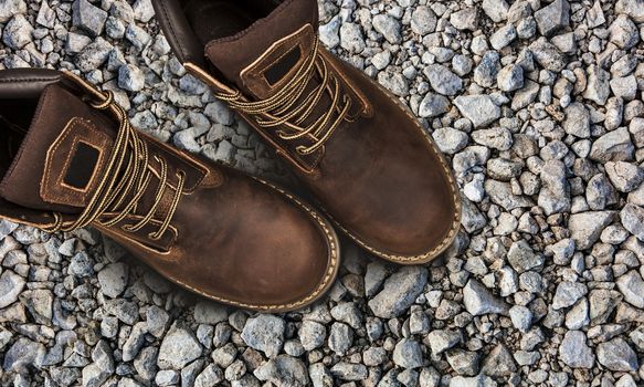 Men's brown boots on stone gravel background. Closeup isolated