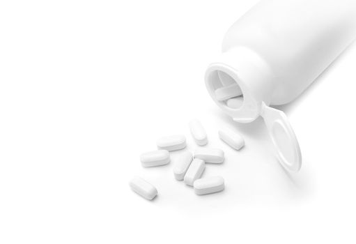 White Pills spilled from a opened bottle isolated on a white background