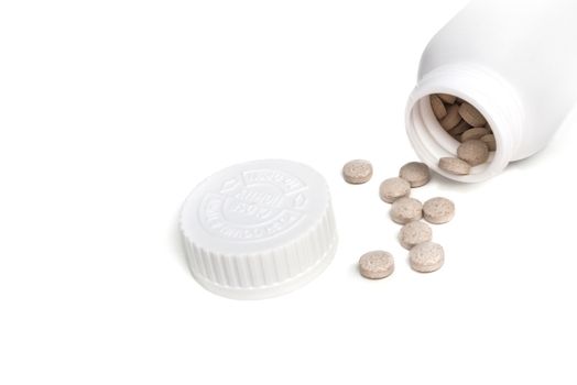 White Pills spilled from a opened bottle isolated on a white background