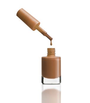 Nail polish dripping from brush into bottle on white background