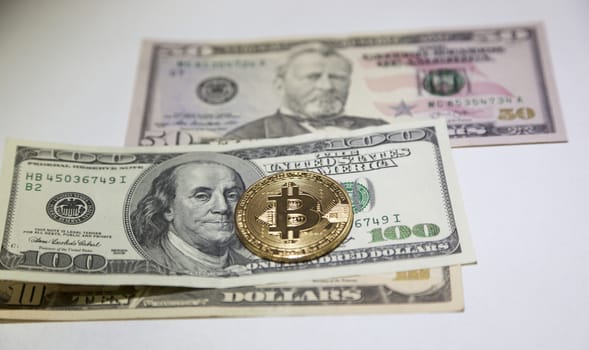 Golden bitcoin coin on us dollars isolated on close up.