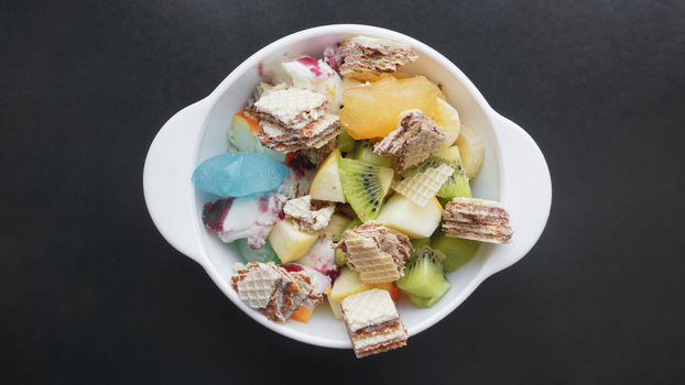 Close up desert with fresh fruit and ice cream. Mixed Fruit With with waffle and fruit ice on black background