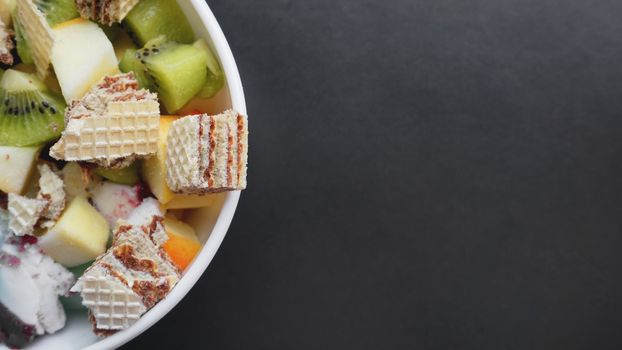 Close up desert with fresh fruit and ice cream. Mixed Fruit With with waffle and fruit ice on black background