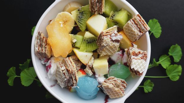 Close up desert with fresh fruit and ice cream. Mixed Fruit With with waffle and fruit ice on black background