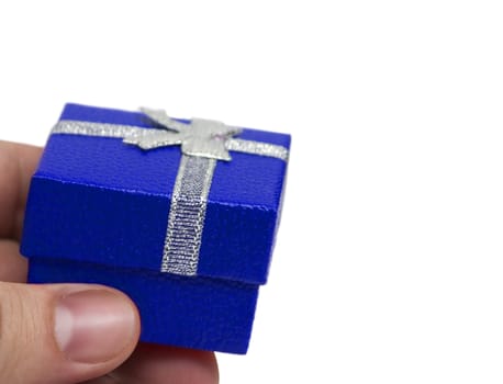Hand holding small blue gift with silver ribbon isolated on white background