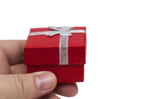 Hand holding small red gift with silver ribbon isolated on white background