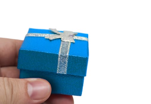 Hand holding small blue gift with silver ribbon isolated on white background