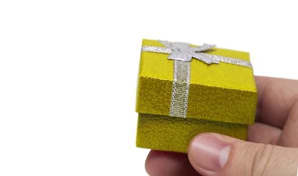 Hand holding small yellow collour gift with silver ribbon isolated on white background