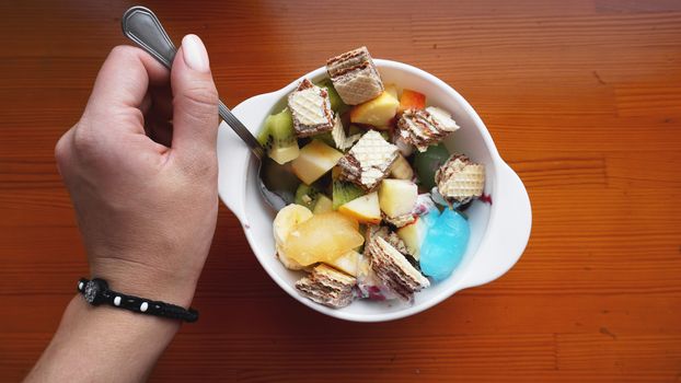 Close up desert with hand. fresh fruit and ice cream. Mixed Fruit With with waffle and fruit ice on wooden background