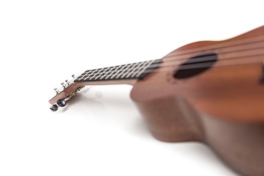 The brown ukulele guitar isolated on the white background. Blurred concept