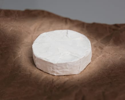 Fresh Camembert cheese is a natural, on Kraft paper brown background. With clipping path