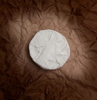 Fresh Camembert cheese is a natural, on Kraft paper brown background. With clipping path