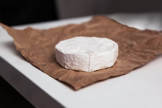 Fresh Camembert cheese is a natural, on Kraft paper brown background. With clipping path