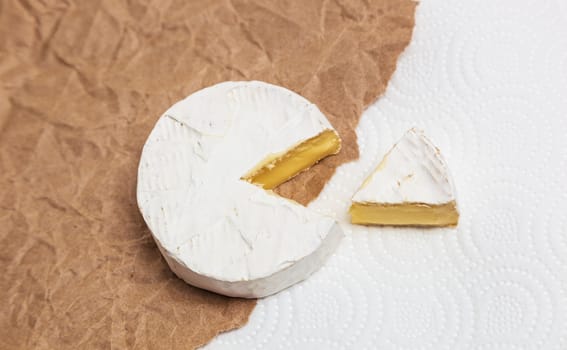 Fresh slice Camembert cheese natural, on Kraft paper brown background. With clipping path