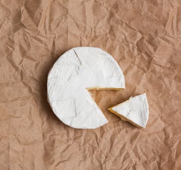 Fresh slice Camembert cheese natural, on Kraft paper brown background. With clipping path