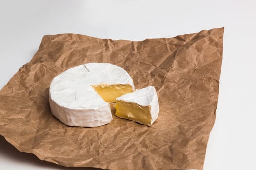 Fresh slice Camembert cheese natural, on Kraft paper brown background. With clipping path