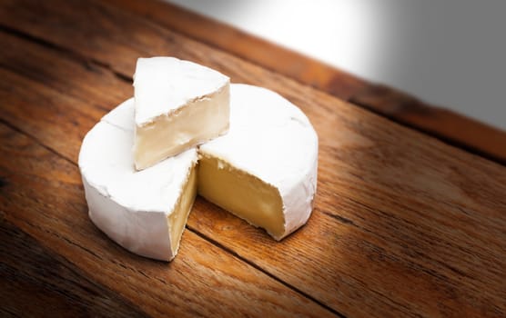 French Camembert cheese on rustic wooden table background